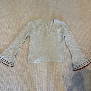 grey sweater with mauve orange detailing on the sleeve